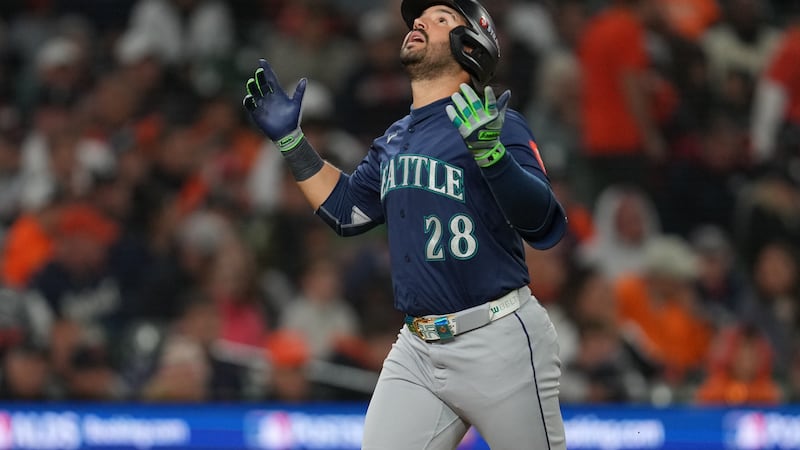 Seattle Mariners' Eugenio Suárez (28) arrives home after hitting a solo home run during the...