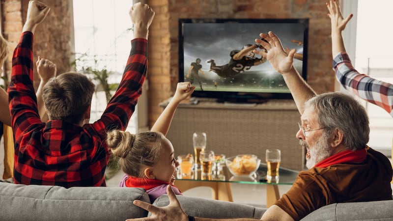 Family cheering for their favorite sports team, who they are watching on a NEXTGENTV in their...